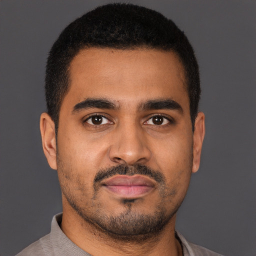 Joyful black young-adult male with short  brown hair and brown eyes