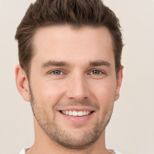 Joyful white young-adult male with short  brown hair and grey eyes