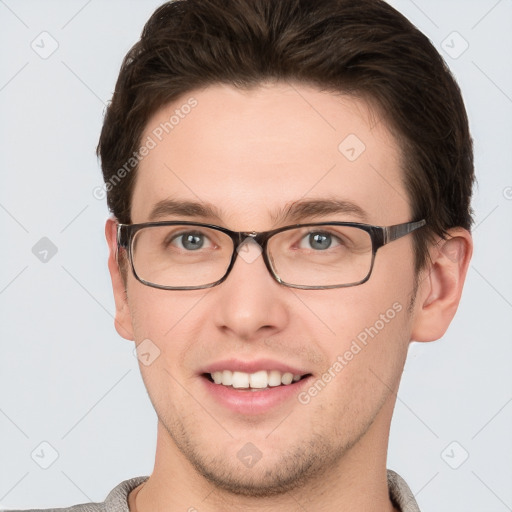 Joyful white young-adult male with short  brown hair and grey eyes