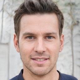 Joyful white young-adult male with short  brown hair and grey eyes