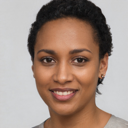 Joyful black young-adult female with short  black hair and brown eyes