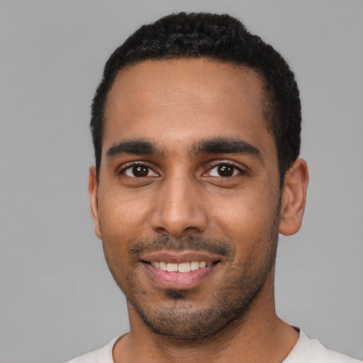 Joyful black young-adult male with short  black hair and brown eyes