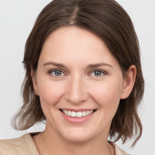 Joyful white young-adult female with medium  brown hair and grey eyes