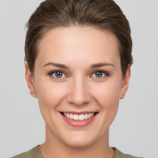 Joyful white young-adult female with short  brown hair and grey eyes