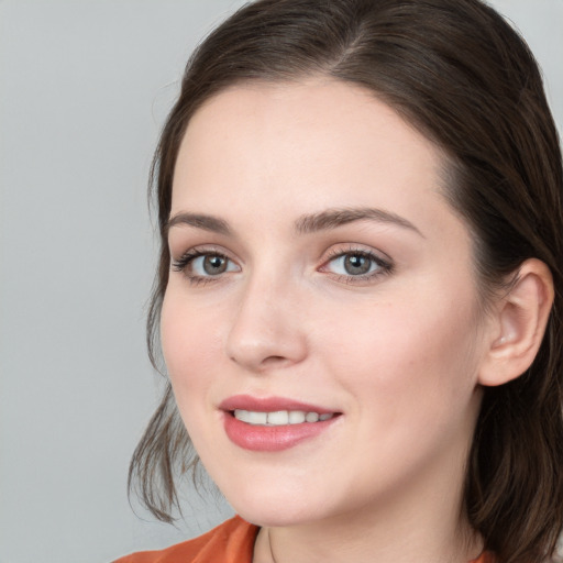 Joyful white young-adult female with medium  brown hair and grey eyes