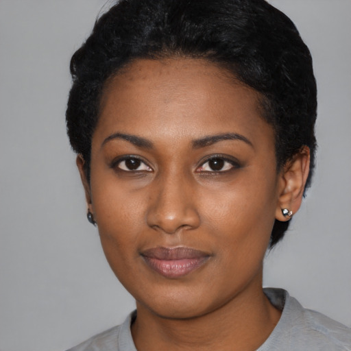 Joyful black young-adult female with short  black hair and brown eyes
