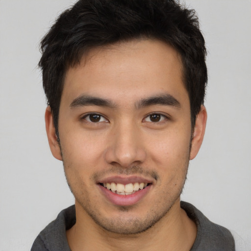 Joyful asian young-adult male with short  brown hair and brown eyes