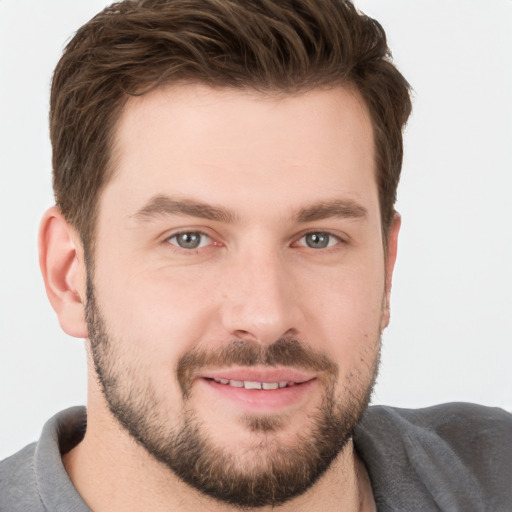 Joyful white young-adult male with short  brown hair and grey eyes