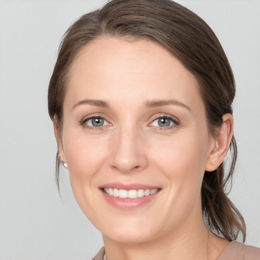 Joyful white young-adult female with medium  brown hair and grey eyes