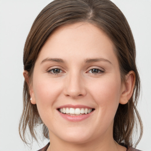 Joyful white young-adult female with medium  brown hair and grey eyes