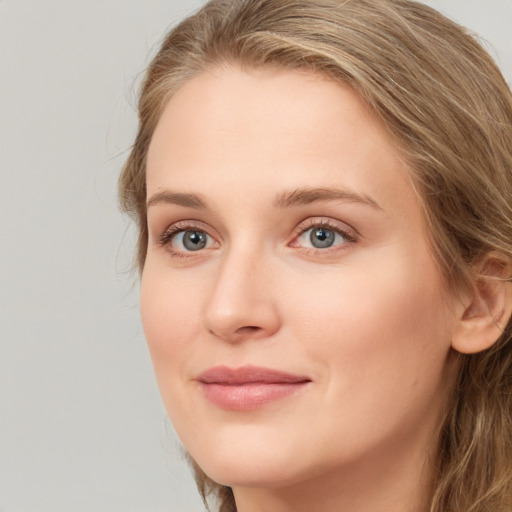 Joyful white young-adult female with long  brown hair and blue eyes