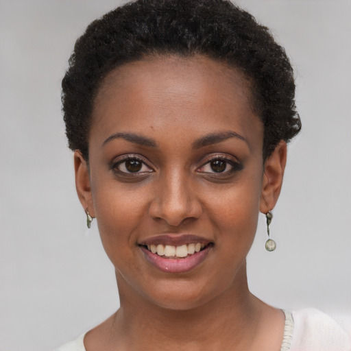 Joyful black young-adult female with short  black hair and brown eyes