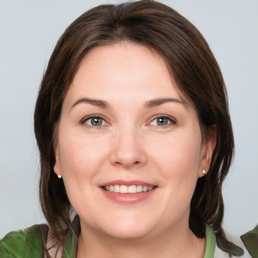 Joyful white young-adult female with medium  brown hair and green eyes