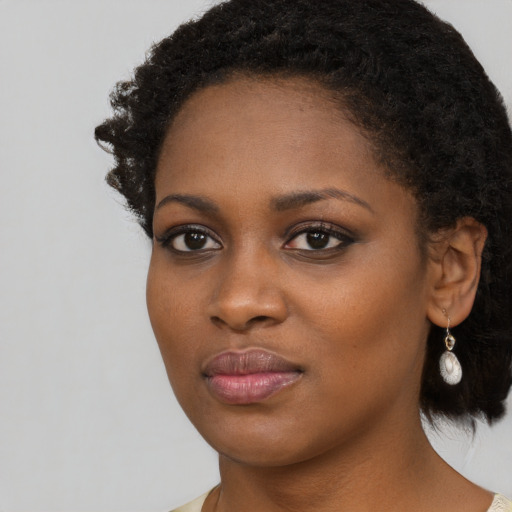 Joyful black young-adult female with short  black hair and brown eyes
