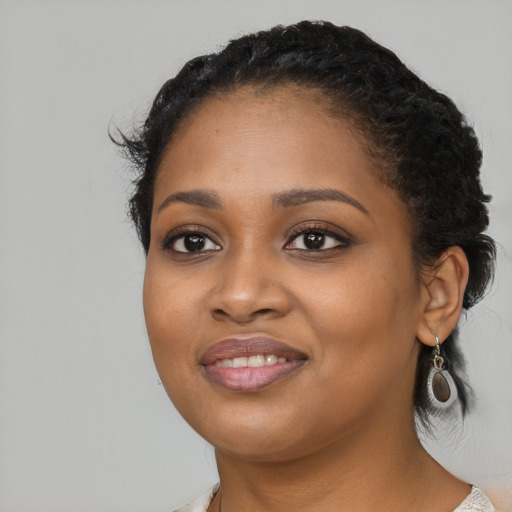 Joyful black young-adult female with long  black hair and brown eyes
