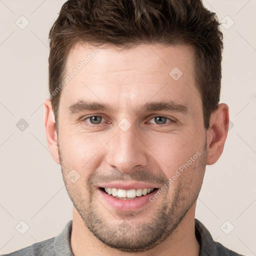 Joyful white young-adult male with short  brown hair and grey eyes