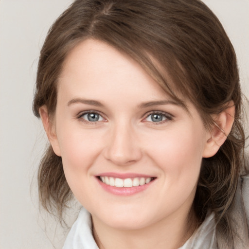 Joyful white young-adult female with medium  brown hair and grey eyes