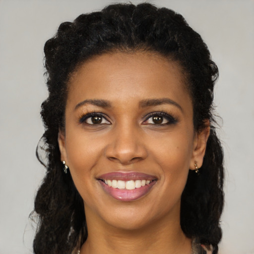 Joyful black young-adult female with long  black hair and brown eyes