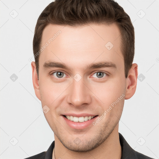 Joyful white young-adult male with short  brown hair and grey eyes