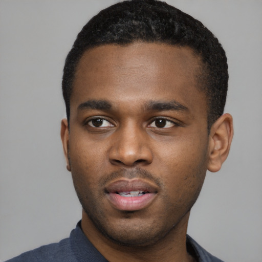 Joyful black young-adult male with short  black hair and brown eyes