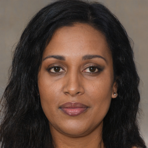 Joyful black young-adult female with long  brown hair and brown eyes