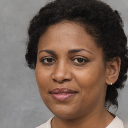 Joyful black adult female with medium  brown hair and brown eyes