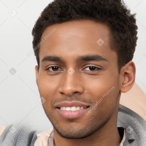 Joyful black young-adult male with short  brown hair and brown eyes