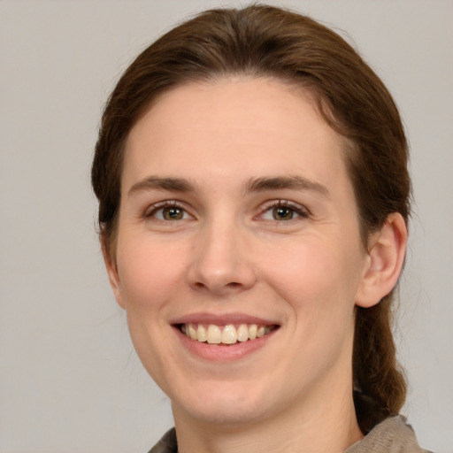 Joyful white young-adult female with medium  brown hair and green eyes