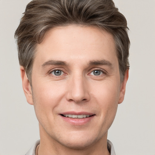 Joyful white young-adult male with short  brown hair and grey eyes