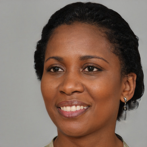 Joyful black young-adult female with short  black hair and brown eyes