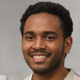 Joyful black young-adult male with short  black hair and brown eyes