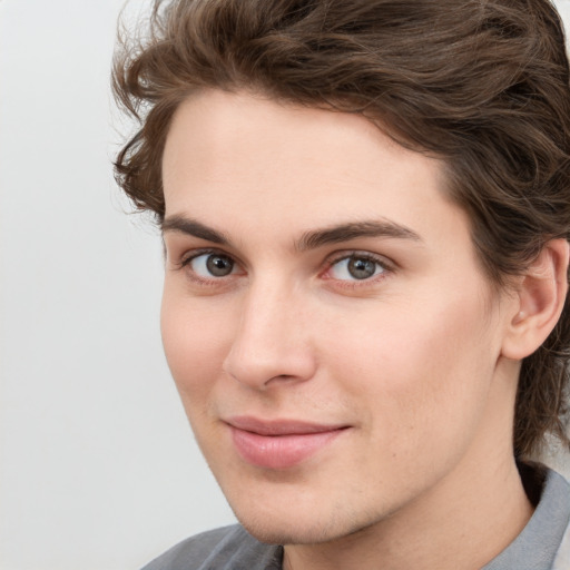 Joyful white young-adult male with medium  brown hair and grey eyes