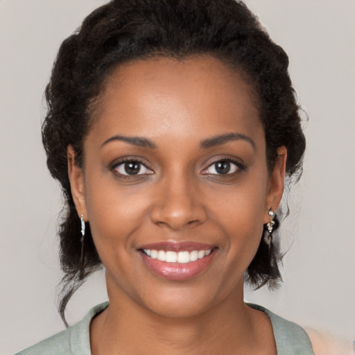 Joyful black young-adult female with long  brown hair and brown eyes