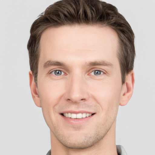 Joyful white young-adult male with short  brown hair and grey eyes