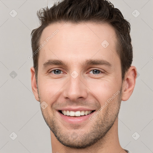 Joyful white young-adult male with short  brown hair and grey eyes