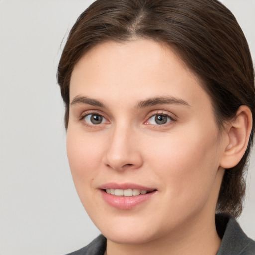 Joyful white young-adult female with medium  brown hair and grey eyes