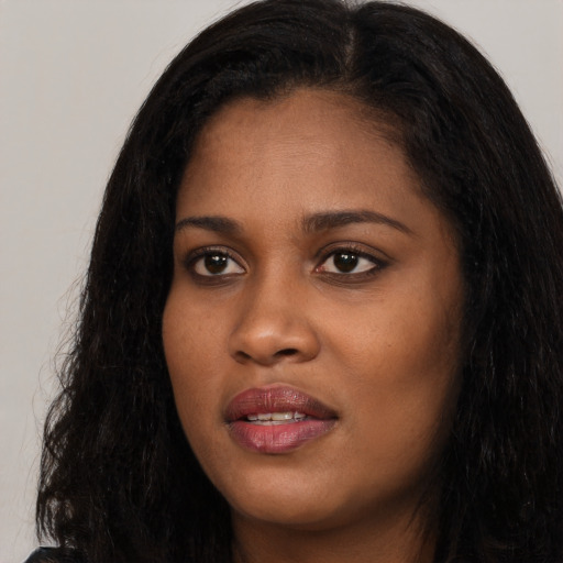 Joyful black young-adult female with long  black hair and brown eyes