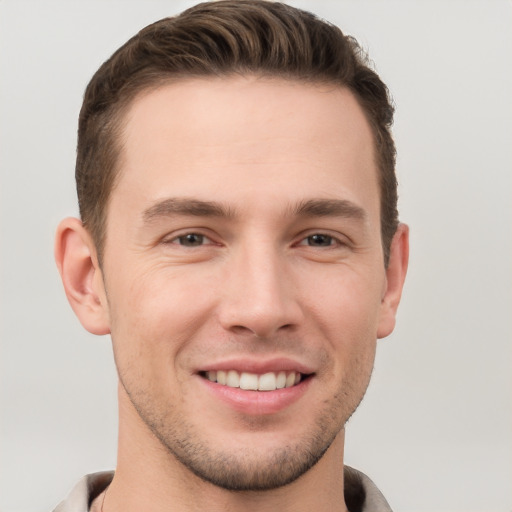 Joyful white young-adult male with short  brown hair and grey eyes