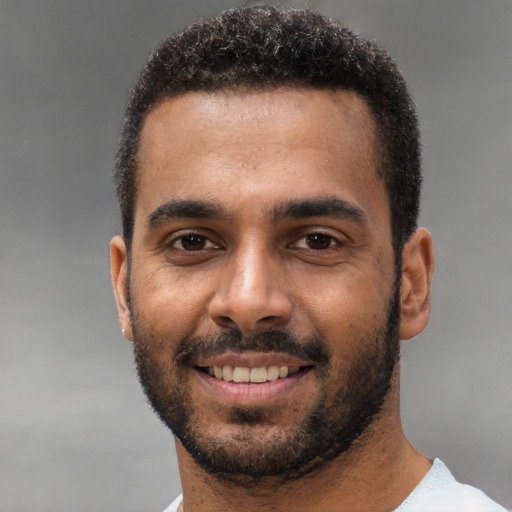 Joyful black young-adult male with short  black hair and brown eyes