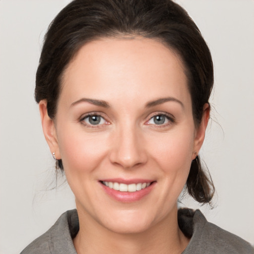 Joyful white young-adult female with medium  brown hair and grey eyes