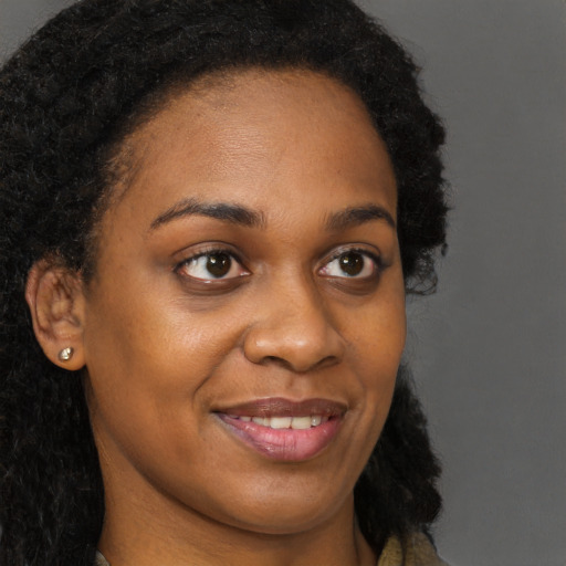 Joyful black young-adult female with long  brown hair and brown eyes
