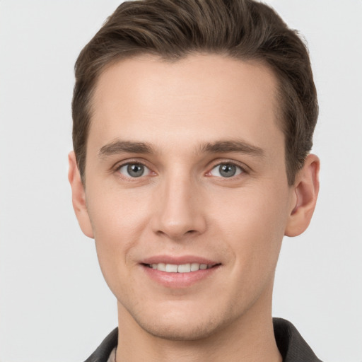 Joyful white young-adult male with short  brown hair and grey eyes