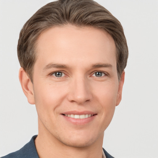 Joyful white young-adult male with short  brown hair and grey eyes