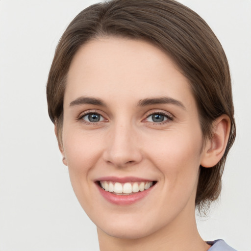 Joyful white young-adult female with medium  brown hair and grey eyes