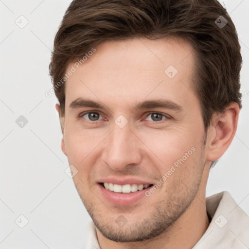 Joyful white young-adult male with short  brown hair and grey eyes