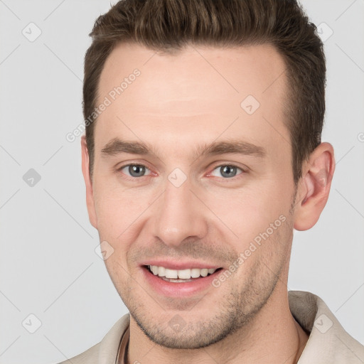 Joyful white young-adult male with short  brown hair and grey eyes