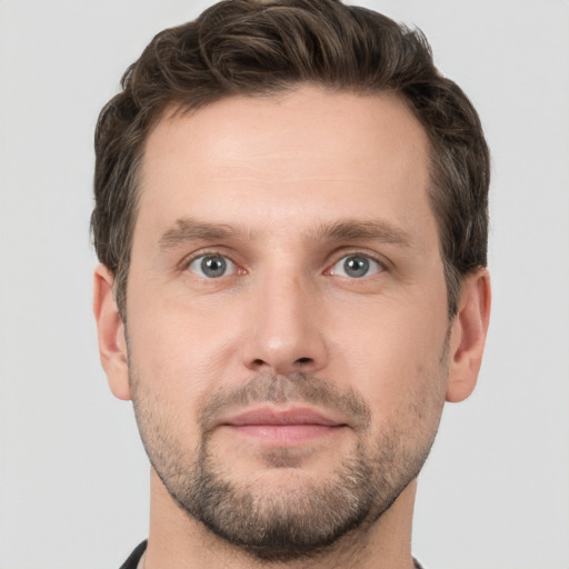 Joyful white young-adult male with short  brown hair and grey eyes