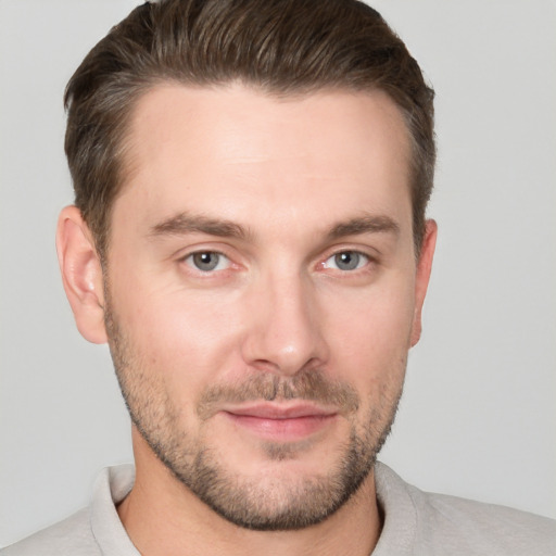 Joyful white young-adult male with short  brown hair and grey eyes