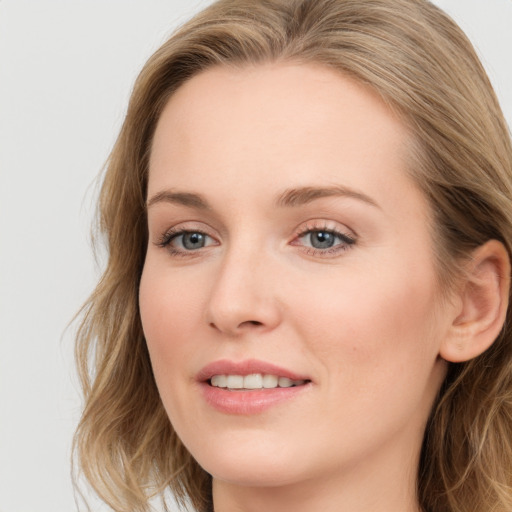 Joyful white young-adult female with long  brown hair and blue eyes