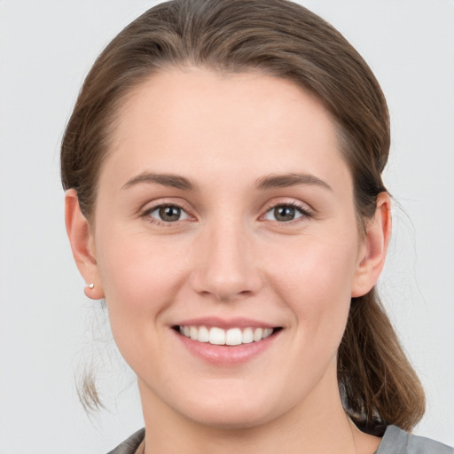 Joyful white young-adult female with medium  brown hair and grey eyes